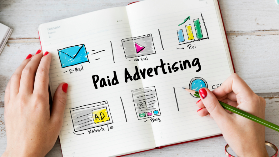 Carnet de notes avec le titre Paid Advertising entouré de dessins d'e-mail marketing, vidéo virale, graphique de ROI, blog et publicité web