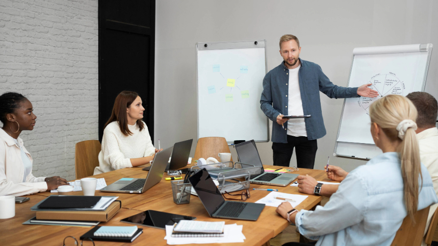 Groupe de professionnels en pleine séance de formation marketing digital avec un formateur devant un tableau blanc.